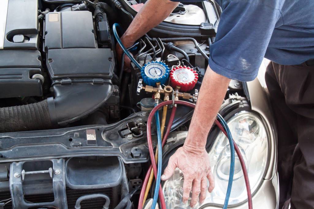 A mechanic checks the evaporator core of a car’s air conditioning system for bacterial growth